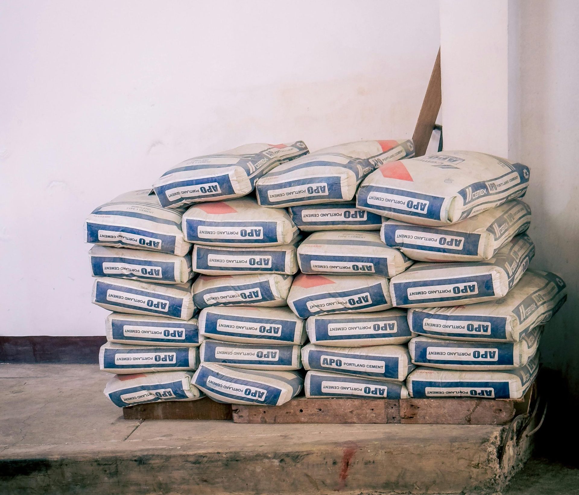 A stack of bags of cement neatly arranged in an indoor warehouse environment.