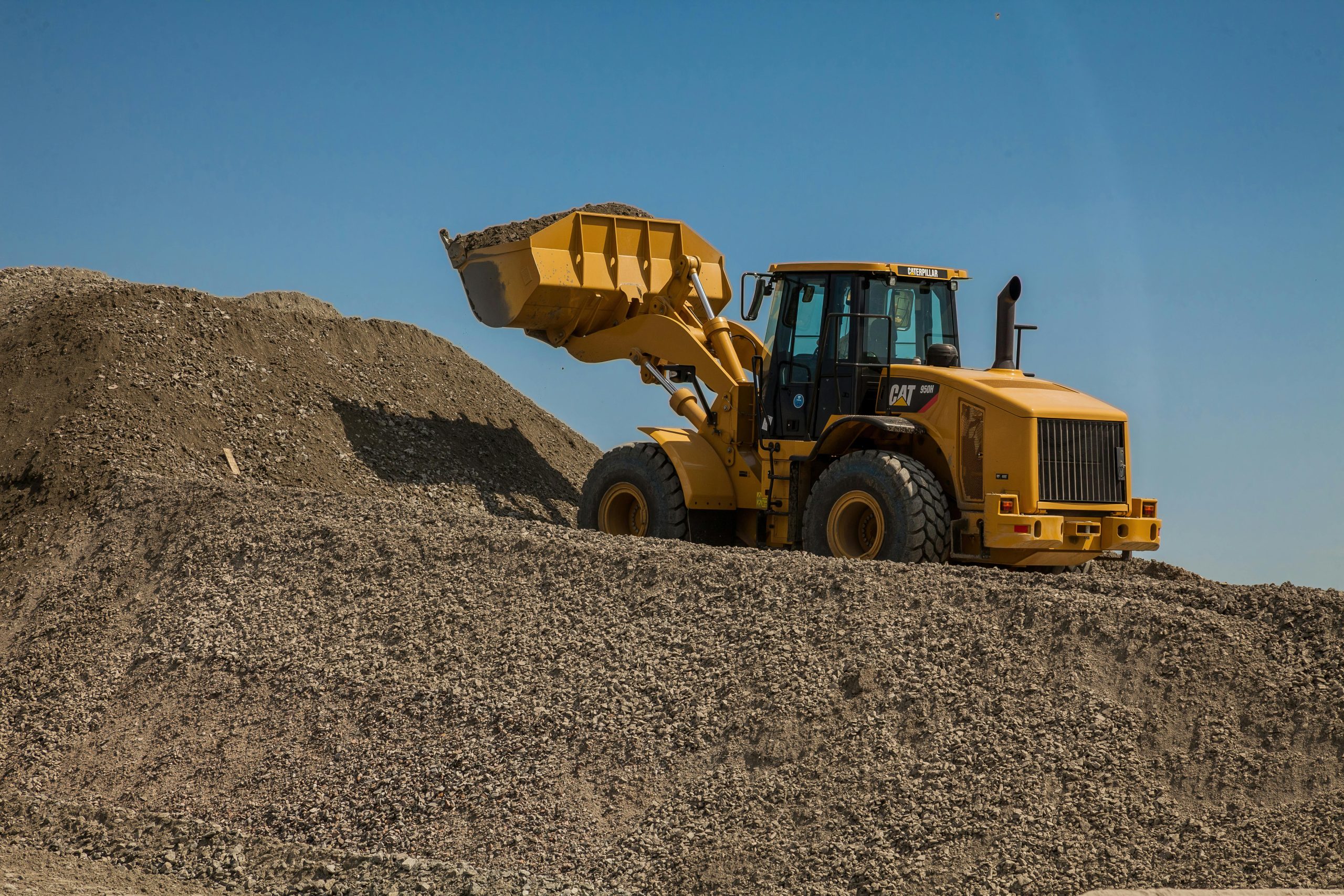 Heavy construction equipment: A powerful front loader in a quarry loads a bucket with crushed stone.